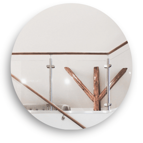 Garde-corps intérieur en verre avec poteaux en acier inoxydable et main courante bois, installé devant un élément décoratif en bois.