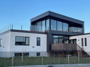 Garde-corps sans poteaux autour d’une terrasse toit sur villa moderne – grandes fenêtres et style épuré.